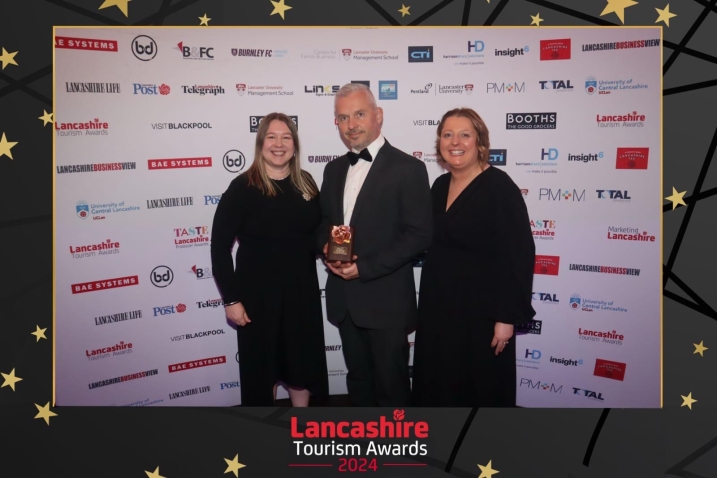 Three members of WWT Martin Mere staff stand with a gold trophy for the Ethical, Responsible & Sustainable Tourism award.